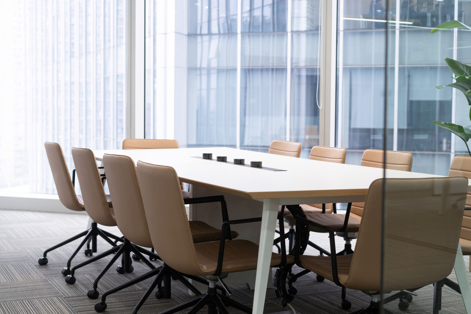 A meeting room with a long table and chairs by a window